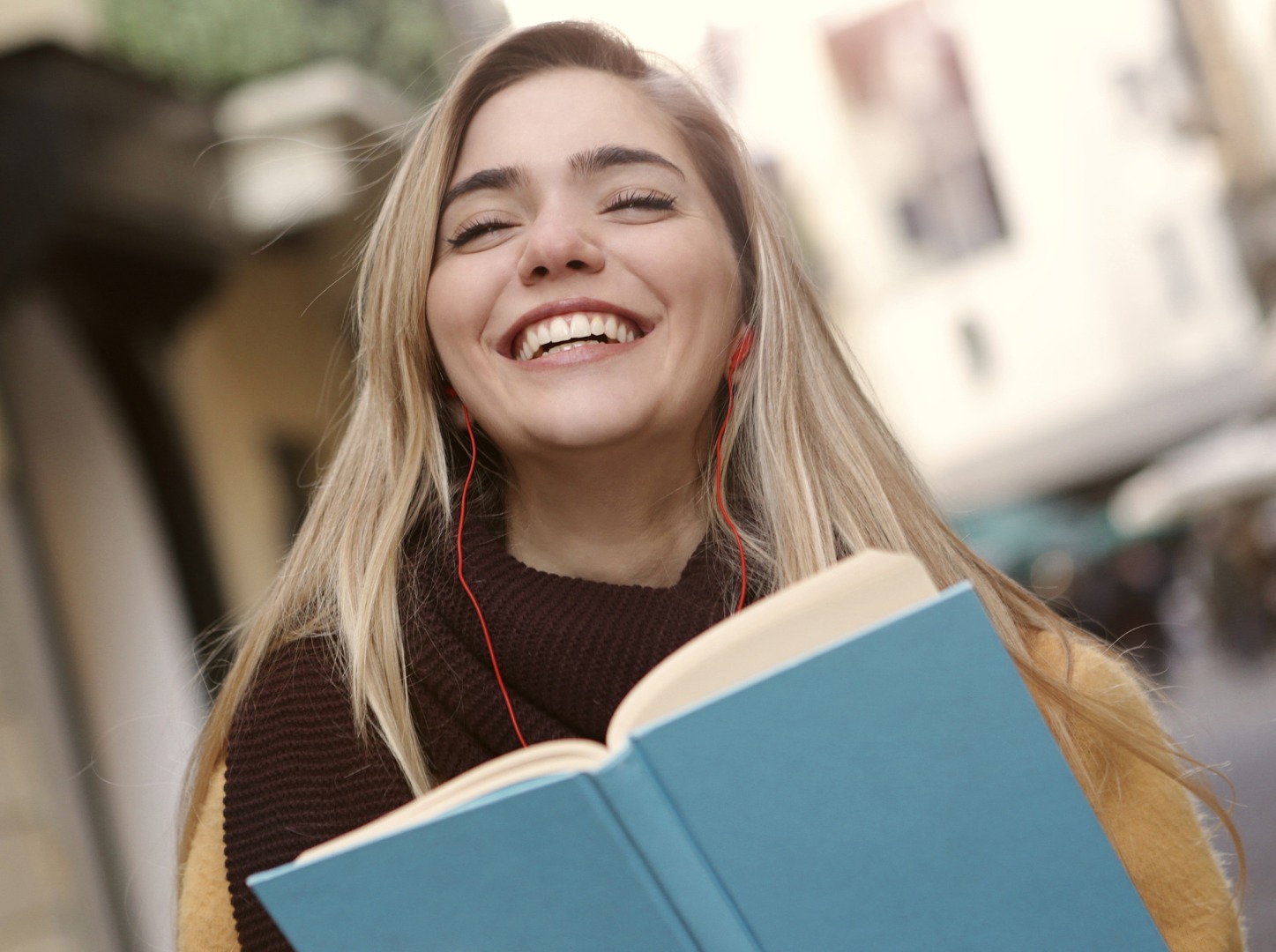 A high school student holds a book, smiling.